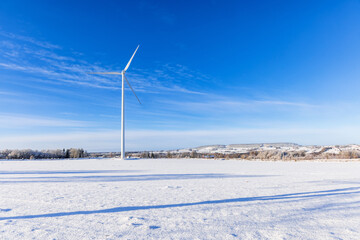 Wintry landscape view with a wind turbine at a snowy field