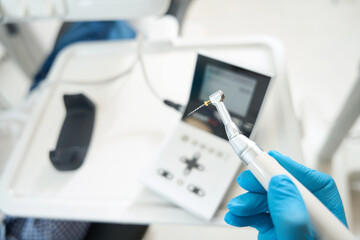 Dentist at his workplace in protective gloves holds thin drill