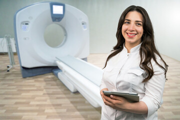 Smiling woman doctor with a digital tablet on the background of a CT scanner