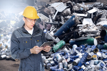 A worker with a digital tablet at a waste recycling plant. Waste management concept