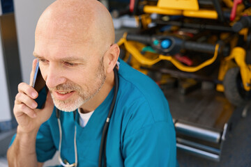 Man talking on phone of open cab of an ambulance