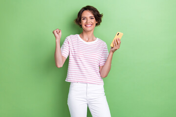 Photo of young adorable pretty smiling toothy girl fist up celebrating youtube million subscribers followers blogger isolated on green color background