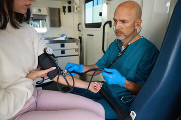 Doctor is measuring internal blood pressure of patient on ambulance