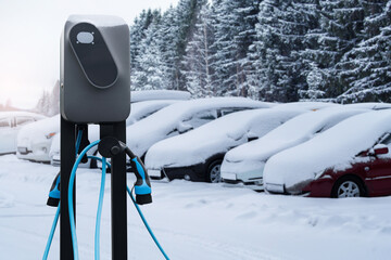 Electric car charging station on a background of snow covered winter cars