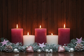 Weihnachtlicher Hintergrund - Weihnachtskerzen in rosa und weiß vor einem Holzhintergrund.