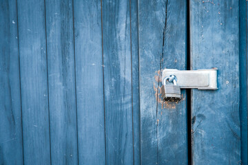 Old padlock and blue boards keep door locked.