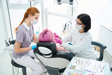 Obraz premium Assistant helps woman doctor in carrying out dental manipulations with patient