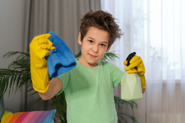 funny boy in rubber gloves holding sponge and spray, ready for house cleaning. portrait of a smiling child who shows cleaning tools