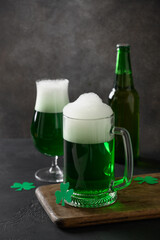 Patrick's day traditional green beer and bottle on dark background. Vertical format.