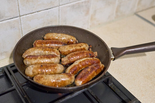 Selective focus of juicy sausages are fried in a pan