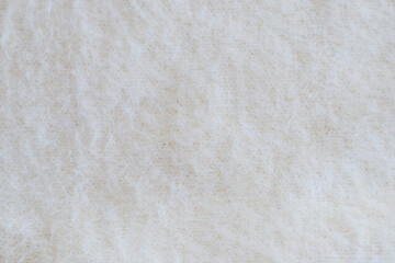 Light background with angora or wool. Soft beige knitted fabric as background, closeup. Fluffy fabric for the whole picture
