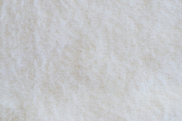 Light background with angora or wool. Soft beige knitted fabric as background, closeup. Fluffy...