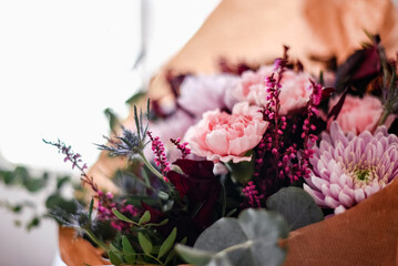 Detalle de las flores de un ramo en tonos rosas y granates. Eucalipto plateado, crisantemo, clavel, peonía y cardo azul.