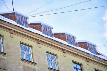 Fototapeta na wymiar Large icicles hanging on the roof of the house in winter time