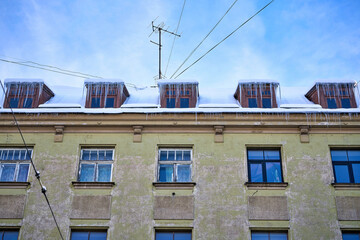 Large icicles hanging on the roof of the house in winter time