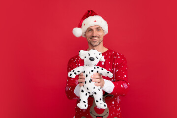 Man in Christmas santa hat hold fluffy toy, gift for baby kids, winter holiday, christmas background.