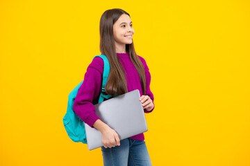 Obraz premium Schoolgirl in school uniform with laptop. Schoolchild, teen student on yellow isolated background.