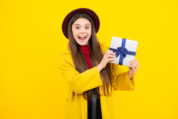 Excited teenager, glad amazed and overjoyed emotions. Teenager child holding gift box on yellow isolated background. Gift for kids birthday. Christmas or New Year present box.