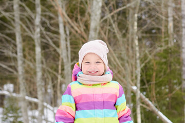 cute cheerful toddler girl in a snowy forest, bright spring sun, snow