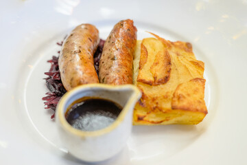 two sausages, potatoes and gravy served on a white plate