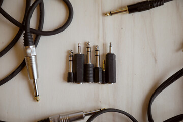 Set of audio jack adapter 6,3 mm and 3,5 mm and various audio jack cables on a wooden bench.Top view. Audio technology and rehearsal room concept.