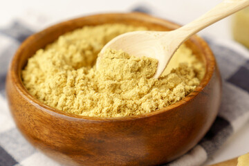 Mustard powder in wooden bowl. Mustards are plants of the genera Brassica and Sinapis.