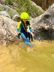 Adrenaline sport - Canyoning. Child with neoprene in mountain ravine
