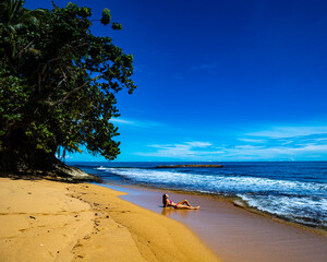 beautiful girl in a bikini lies on the sand on a Caribbean beach in Costa Rica; sunbathing on a paradise beach by the Caribbean sea, beach vacation in tropical Costa Rica