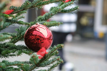 Einkaufen zur Adventszeit: Nahaufnahme einer weihnachtlich geschmückten Tanne mit einer roten...