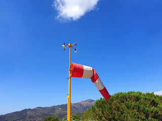 Windsock indicator on blue sky and mountains.