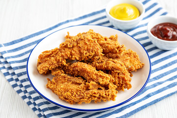 Homemade Chicken Strips with Mustard and BBQ on a Plate, side view.
