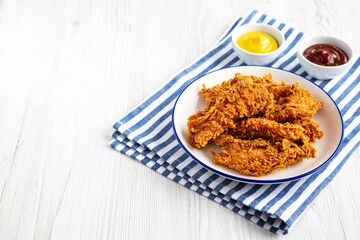Homemade Chicken Strips with Mustard and BBQ on a Plate, side view. Copy space.