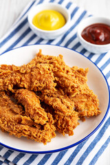 Homemade Chicken Strips with Mustard and BBQ on a Plate, side view.