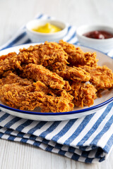 Homemade Chicken Strips with Mustard and BBQ on a Plate, side view.