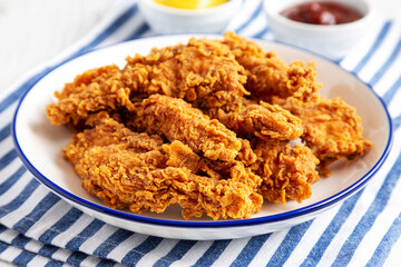 Homemade Chicken Strips with Mustard and BBQ on a Plate, side view. Close-up.