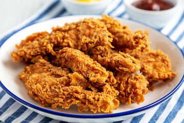 Homemade Chicken Strips with Mustard and BBQ on a Plate, side view. Close-up.