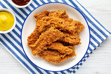 Homemade Chicken Strips with Mustard and BBQ on a Plate, top view. Flat lay, overhead, from above.