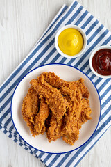 Homemade Chicken Strips with Mustard and BBQ on a Plate, top view. Flat lay, overhead, from above.
