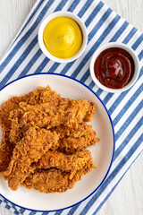 Homemade Chicken Strips with Mustard and BBQ on a Plate, top view. Flat lay, overhead, from above.