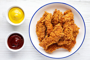 Homemade Chicken Strips with Mustard and BBQ on a Plate, top view. Flat lay, overhead, from above.