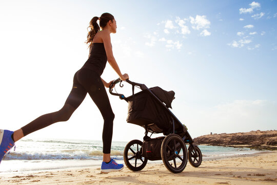 Beautiful mom and son doing a morning jogging on the beach. - Powered by Adobe