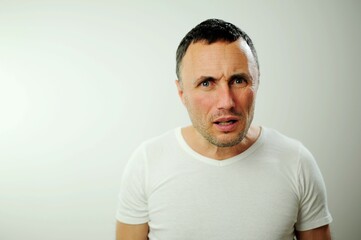 Obraz premium portrait emotional guy feeling sinking heart shortness of breath about emotional stress sensations isolated on grey white studio background, frightened person, horror panic attack concept Appalled man