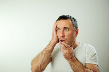 Obraz premium portrait emotional guy feeling sinking heart shortness of breath about emotional stress sensations isolated on grey white studio background, frightened person, horror panic attack concept Appalled man