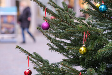 Einkaufen zur Adventszeit: Nahaufnahme einer weihnachtlich geschmückten Tanne mit einer pinken und...