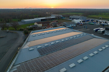Aerial view of solar power plant with blue photovoltaic panels mounted on industrial building roof for producing green ecological electricity. Production of sustainable energy concept