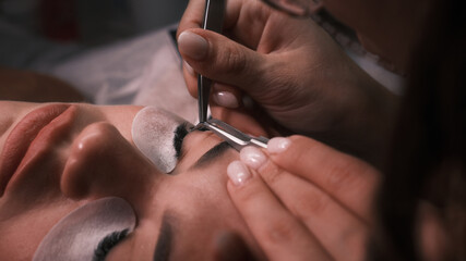 The cosmetologist glues eyelashes on the eye