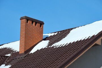 Closeup of house roof top covered with snow in cold winter. Tiled covering of building in...