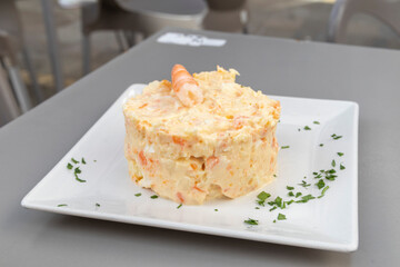 Russian salad with prawns, served on a white plate. Spanish food concept.