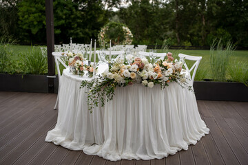 Main table at a wedding reception with beautiful fresh flowers. Outside wedding decorations.