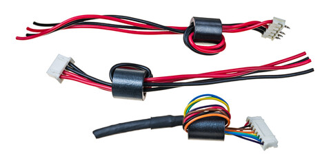 Ferrite bead inductors on insulated wires with plastic connectors isolated on a white background. Set of toroid core chokes as EMI fIlter to block unwanted high frequency noise in electronic circuits.